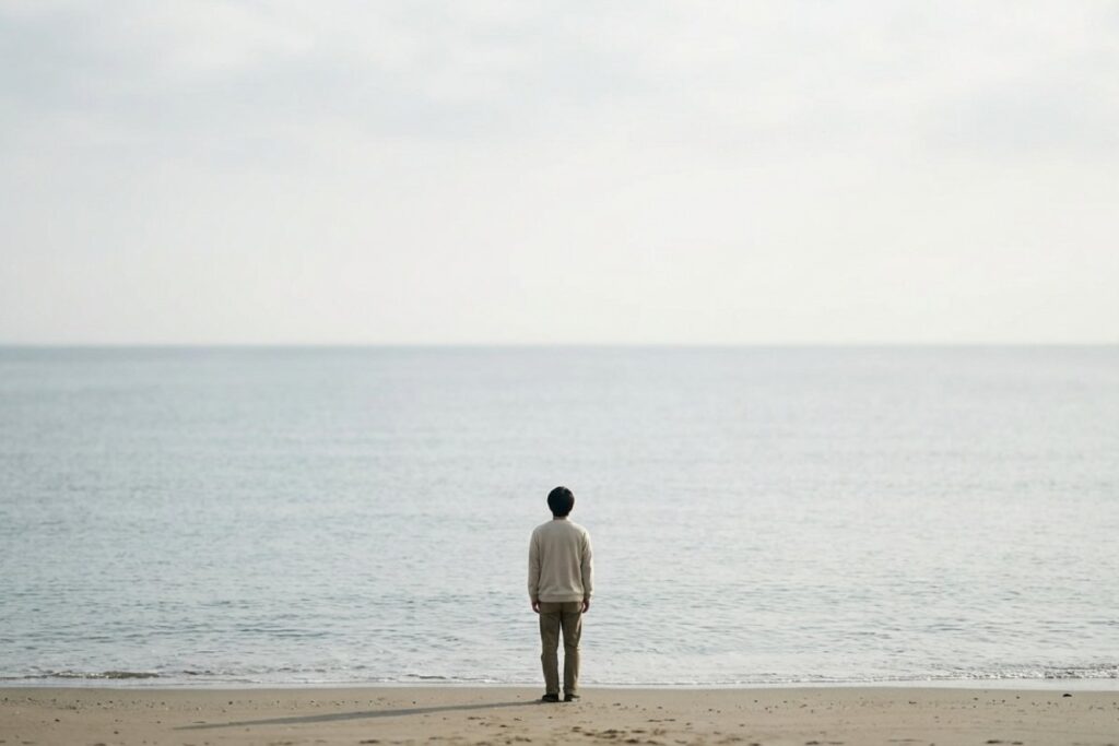 海辺で人物が背中を向けて立ち、水平線を見ている写真。エネルギーを奪う人との距離を意識したイメージ